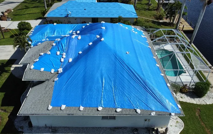 Residential roof covered with a blue tarp after storm damage, awaiting professional roof repair to address leaks and structural issues.