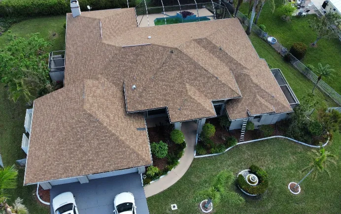 Aerial view of a completed asphalt shingle roof replacement on a residential home, featuring a multi-slope design and fresh installation.